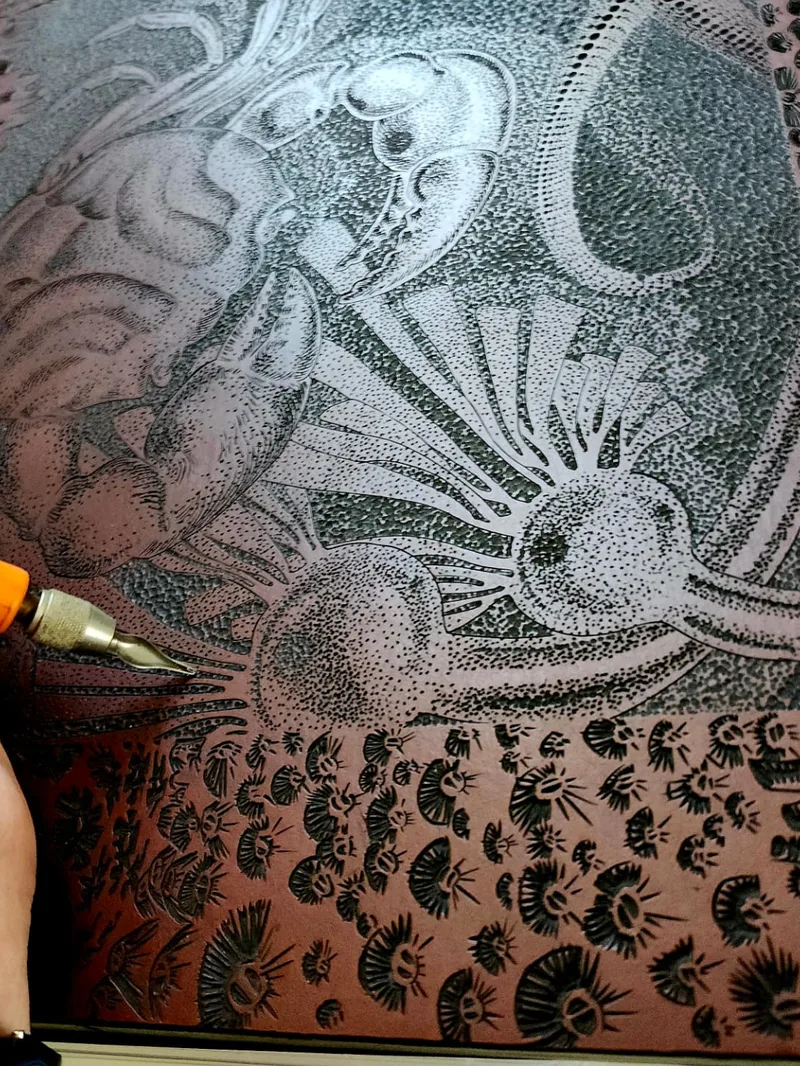 A hand guiding a carving tool across a block in the studio